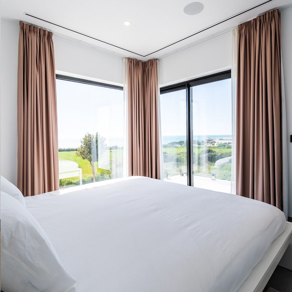Dormitorio principal con grandes ventanales y vistas abiertas al paisaje de Conil.