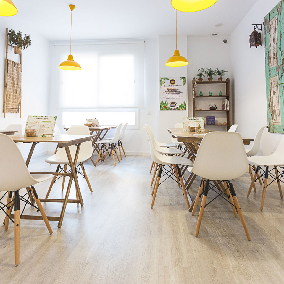 Cafe interior with wooden tables, white chairs and yellow pendant lamps