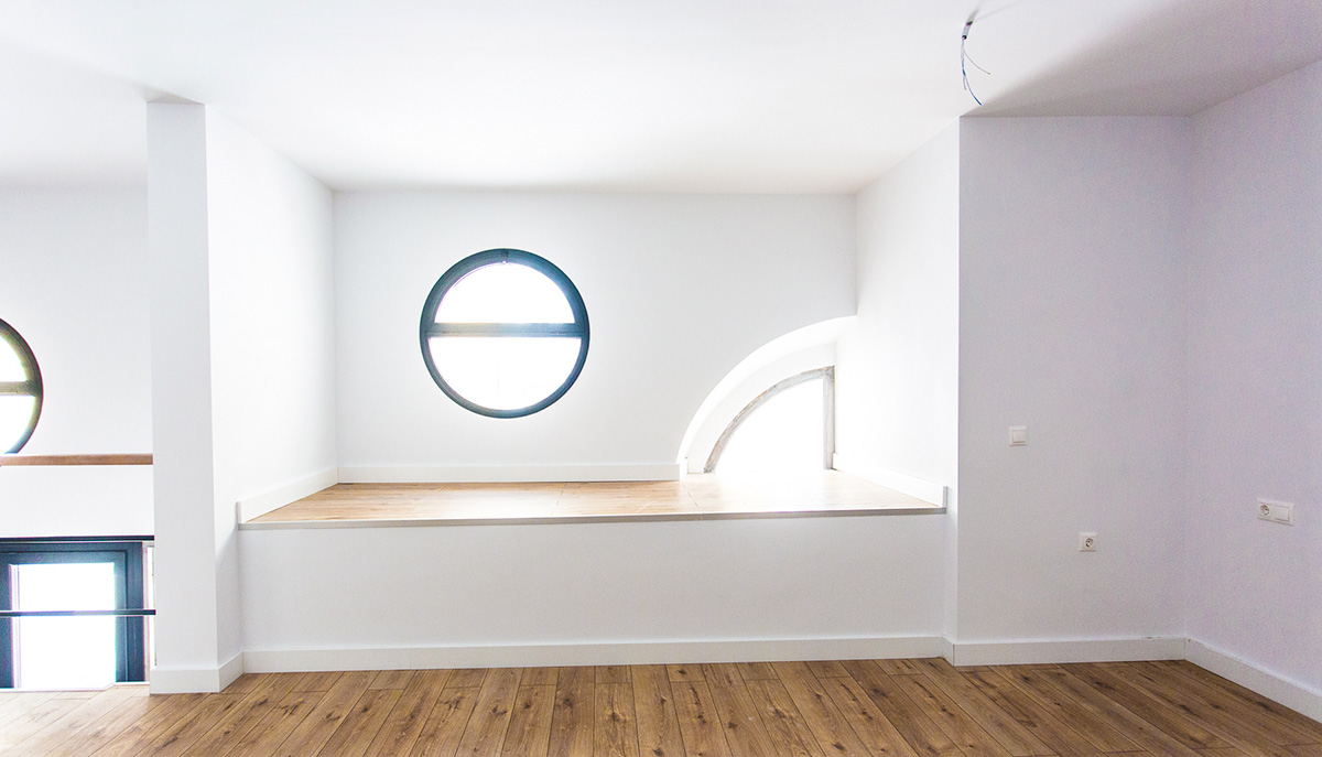 Round skylight in room with white walls and wooden flooring