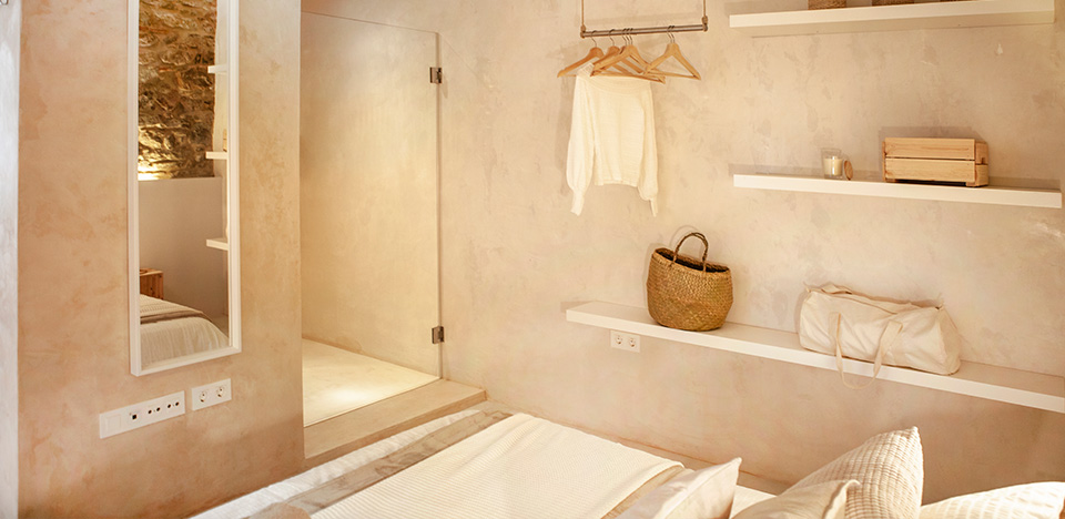Room with a double bed, white shelves and a glass-enclosed shower