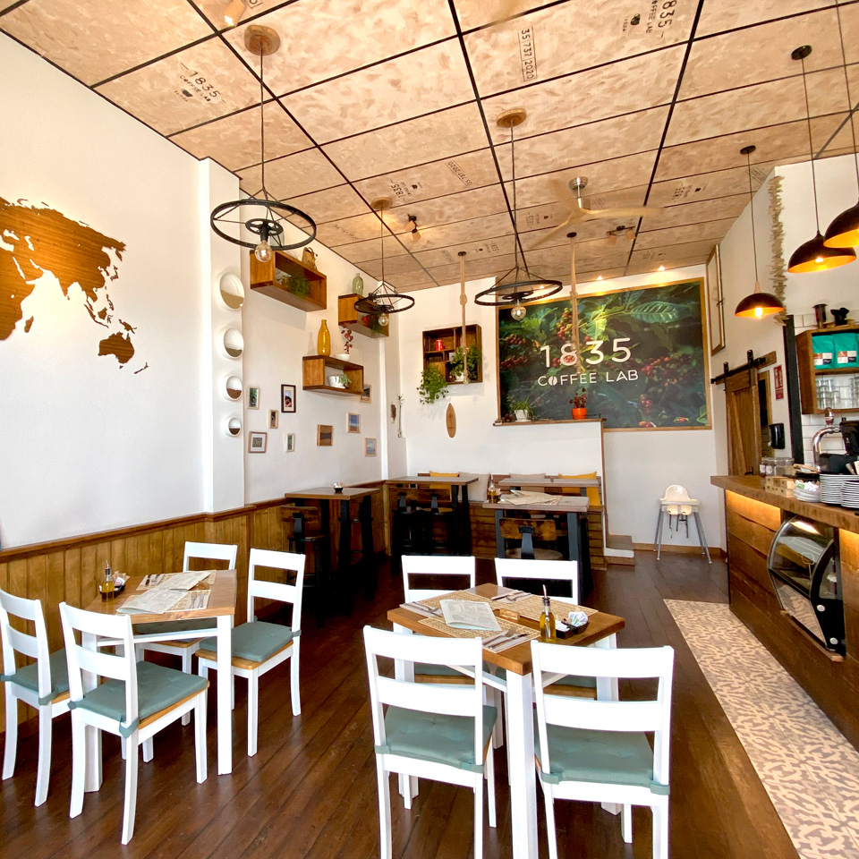 Interior of the Café with the bar, tables and chairs; decorated with maps and shelves on the walls
