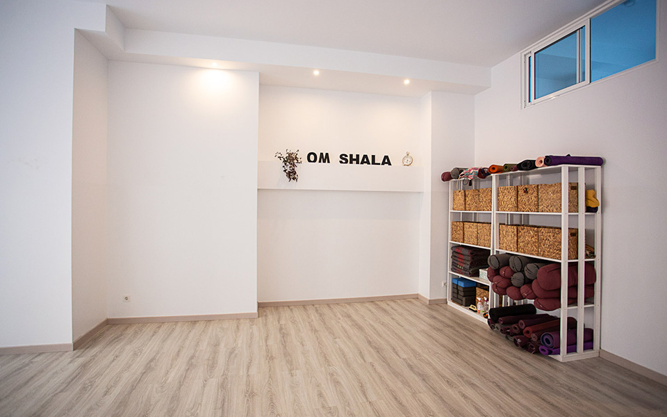 White room with soft brown wooden flooring and cabinet with accessories for yoga
