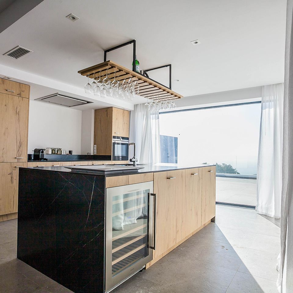 American kitchen in light wood with glass windows overlooking the sea