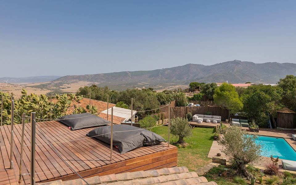 Exterior view with wooden deck with garden, pools and mountain views