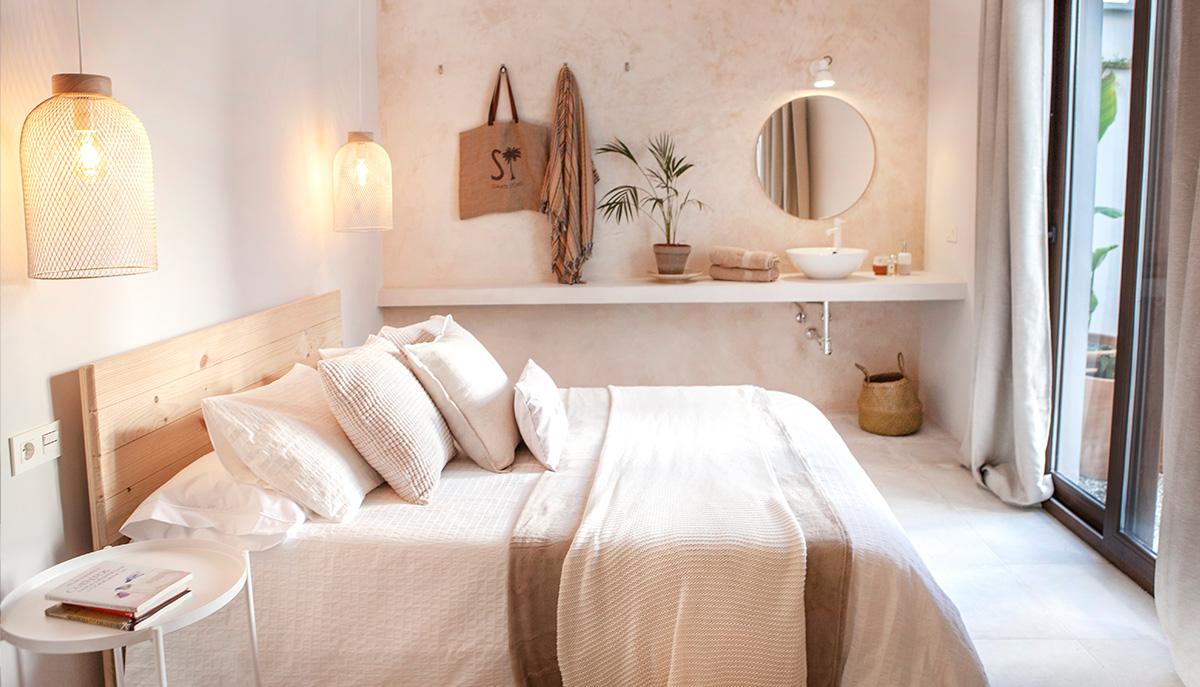 Dormitorio con cama de matrimonio, lavabo blanco y ventana con vistas al patio