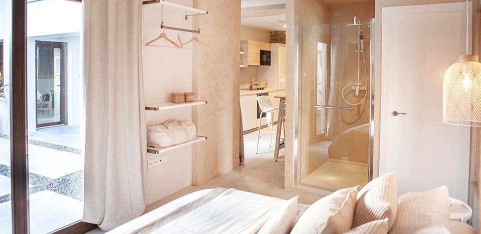 Habitación con cama de matrimonio con ducha con cristalera y ventana al patio