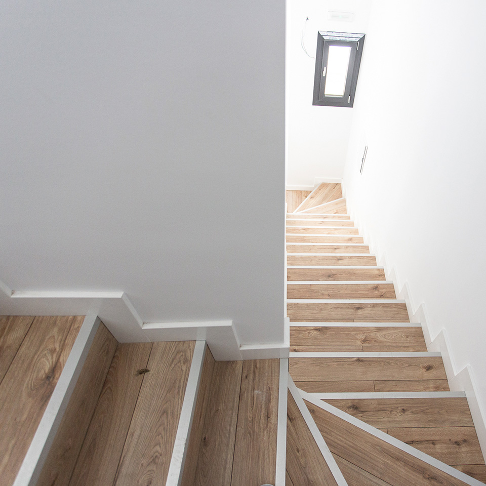 Escalera de bajada con escalones de madera y paredes blancas