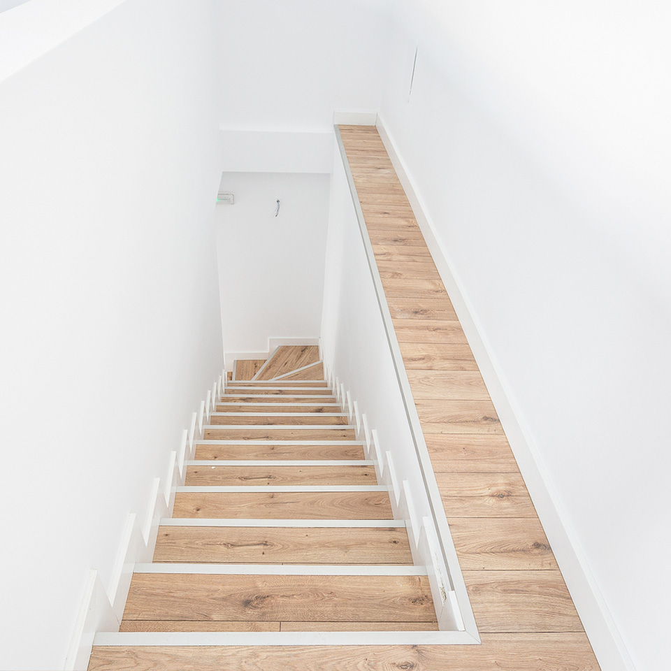 Escalera de bajada con escalones de madera y paredes blancas