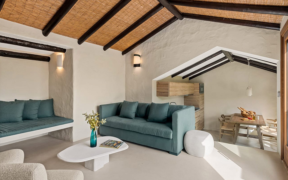 Salón blanco con sofás azules y techos con vigas de madera y brezo