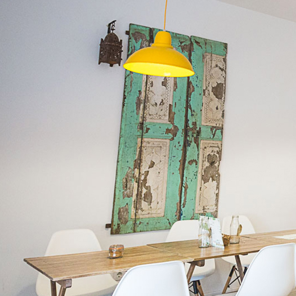 Mesa de comedor con cuadro verde y lámpara amarilla