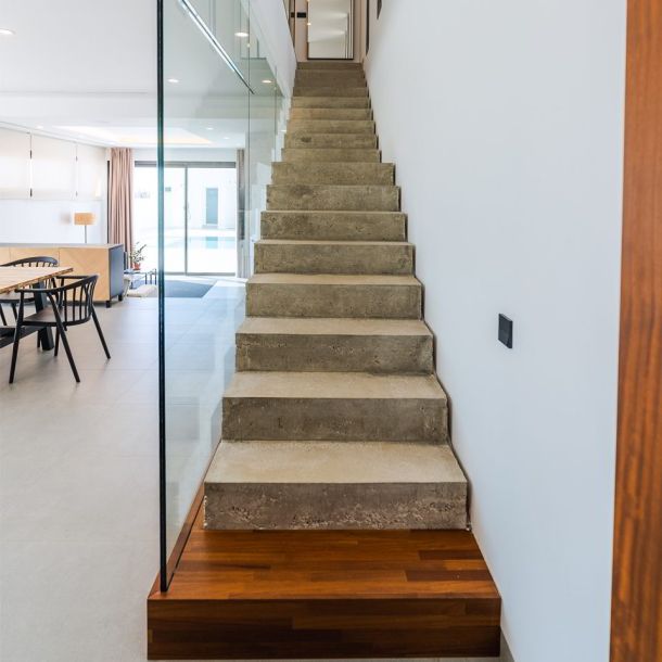 Escalera recta de hormigón visto con peldaños macizos y base de madera natural.