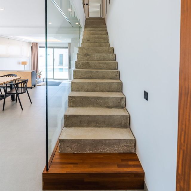 Escalera recta de hormigón visto con peldaños macizos y base de madera natural.