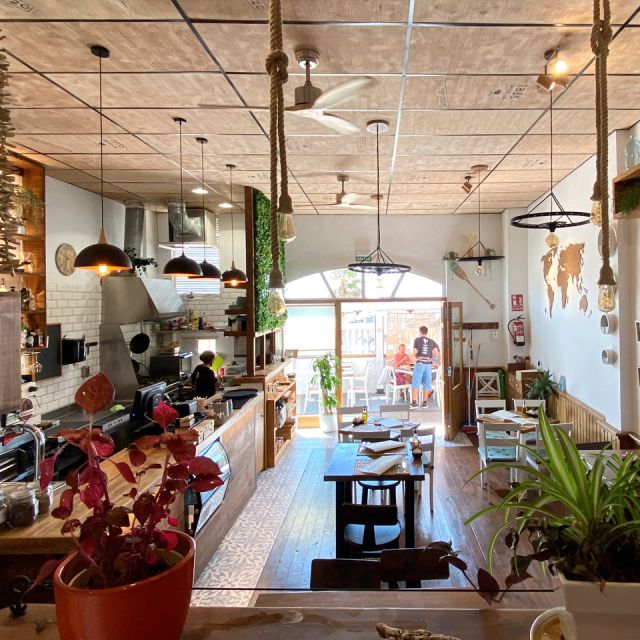 View from inside the Café with the kitchen, bar, tables and glass door with the terrace in the background